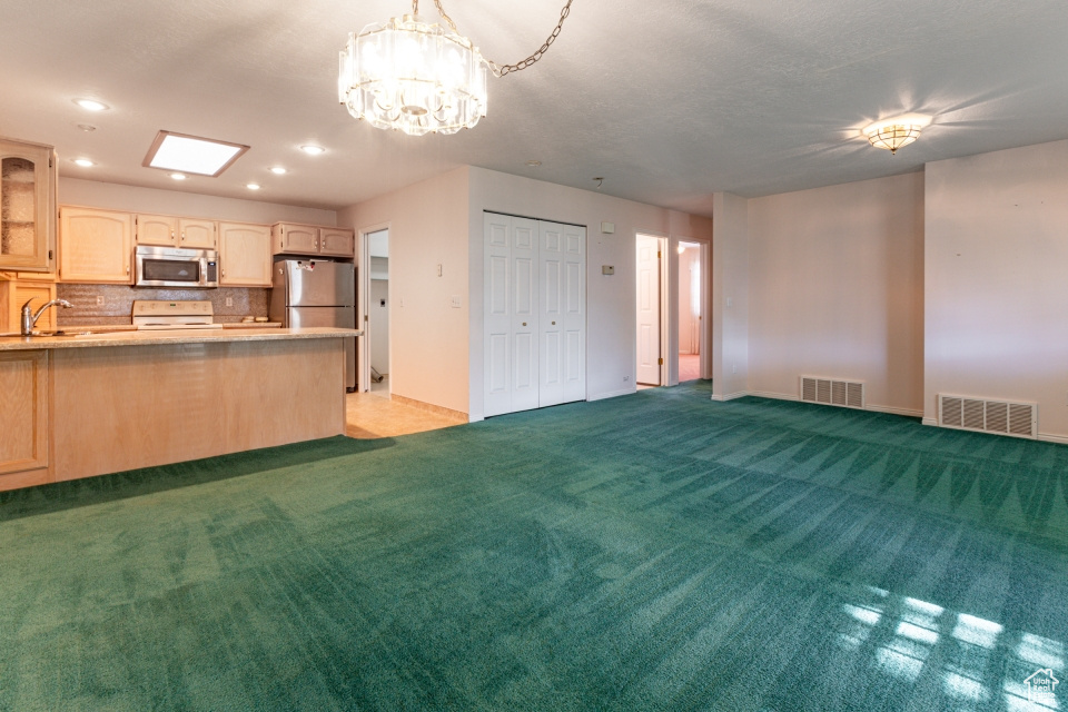 Kitchen featuring visible vents, light colored carpet, light countertops, tasteful backsplash, and appliances with stainless steel finishes