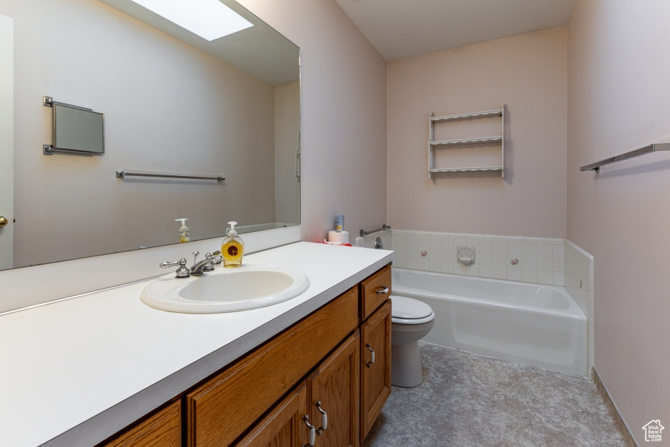 Bathroom featuring a garden tub, toilet, and vanity