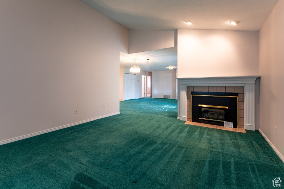 Unfurnished living room with carpet floors, baseboards, visible vents, and a tile fireplace