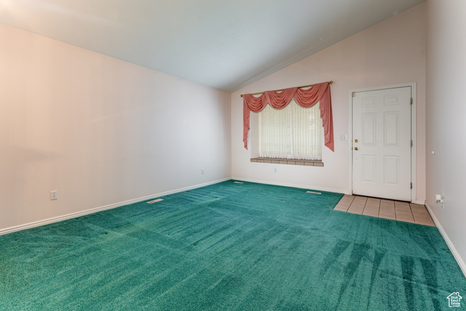 Carpeted spare room with baseboards and vaulted ceiling