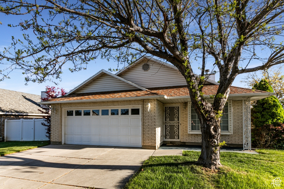 Ranch-style house with fence, a front yard, brick siding, concrete driveway, and an attached garage