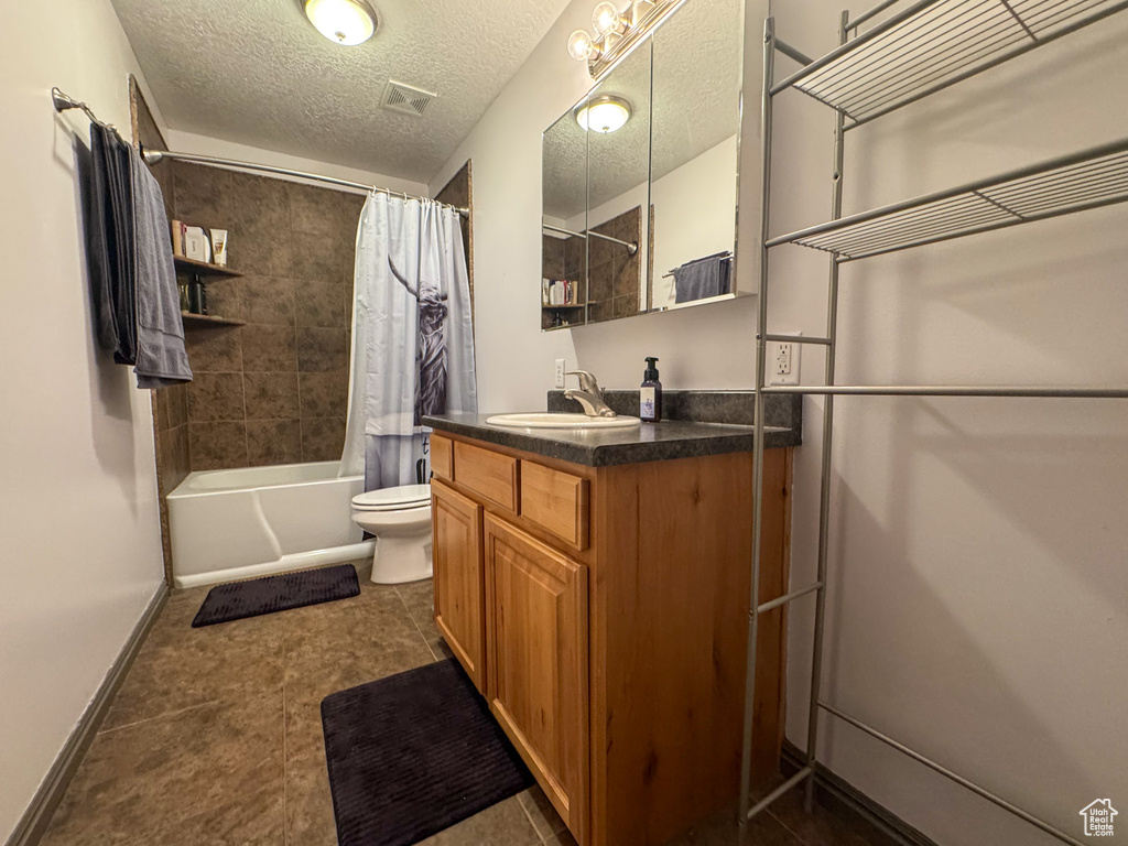 Bathroom featuring visible vents, vanity, toilet, a textured ceiling, and shower / tub combo