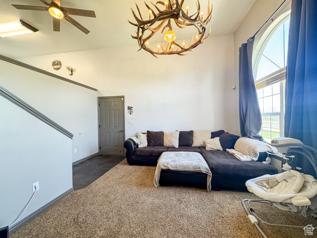 Carpeted living area with ceiling fan with notable chandelier