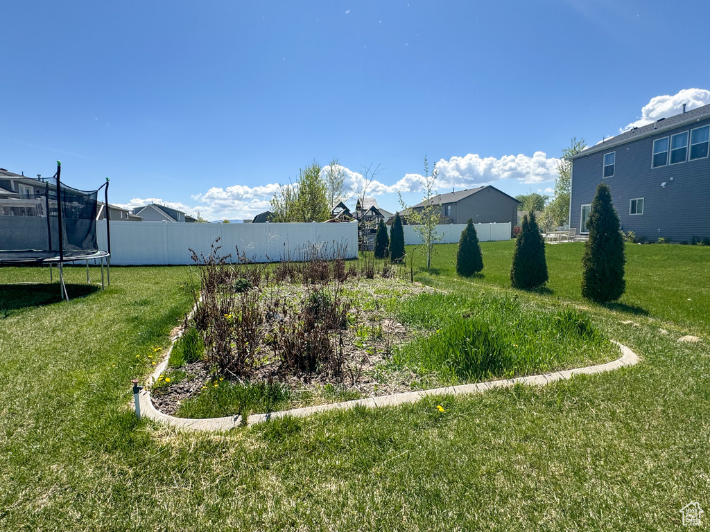 View of yard with a trampoline and fence