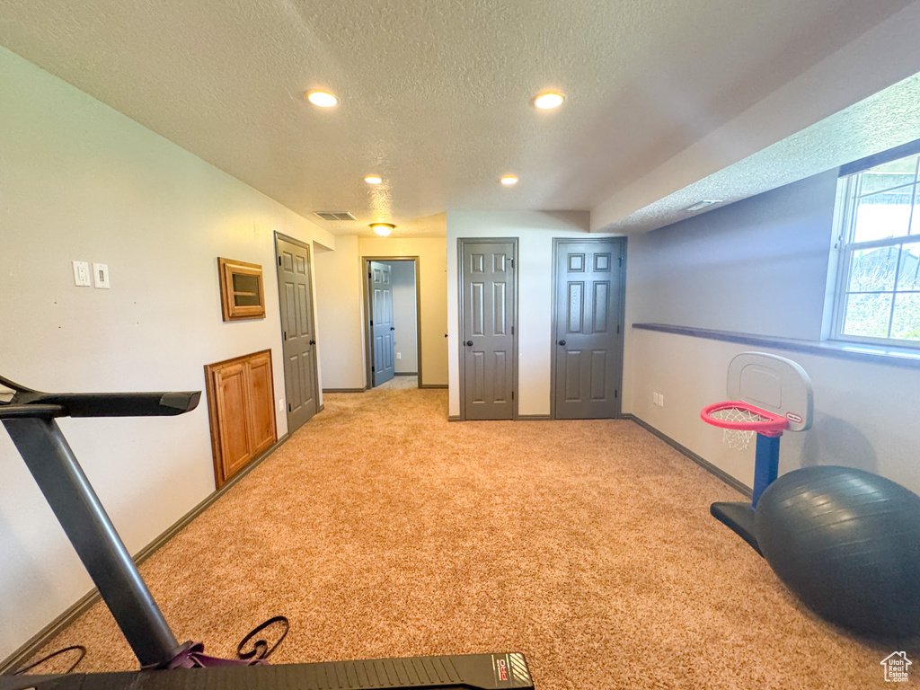 Workout area with recessed lighting, a textured ceiling, baseboards, and light colored carpet