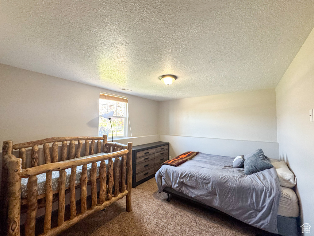 Bedroom with carpet floors, a textured ceiling, and visible vents