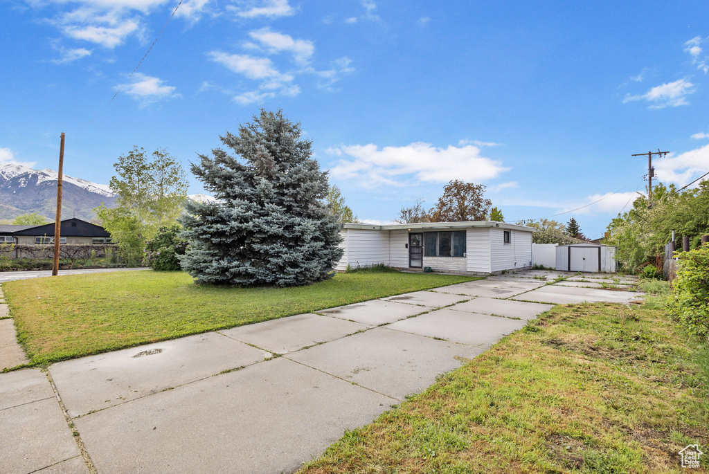 Ranch-style house with driveway, an outbuilding, a shed, and a front lawn
