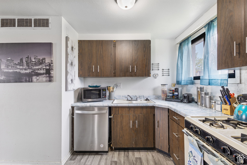 Kitchen featuring visible vents, appliances with stainless steel finishes, a sink, light countertops, and light wood finished floors