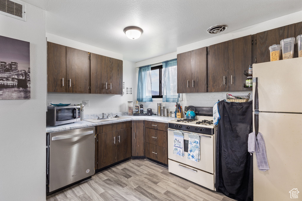 Kitchen with light countertops, stainless steel appliances, visible vents, and dark brown cabinets
