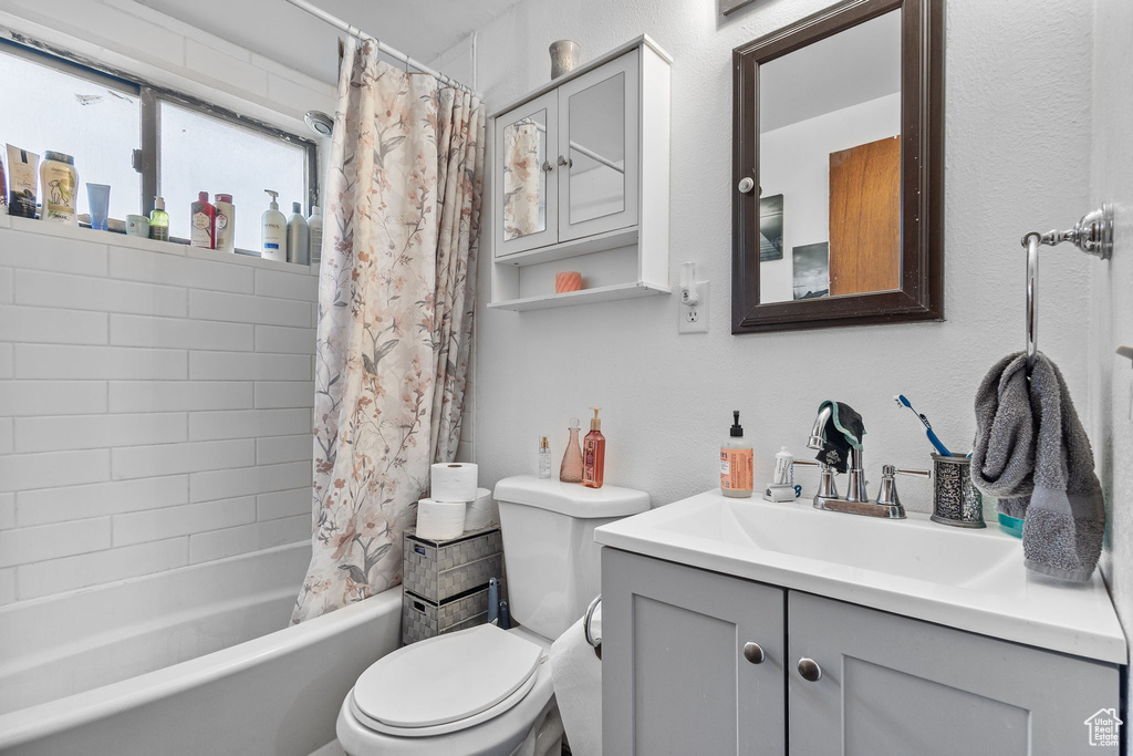 Bathroom featuring vanity, toilet, and shower / bath combination with curtain
