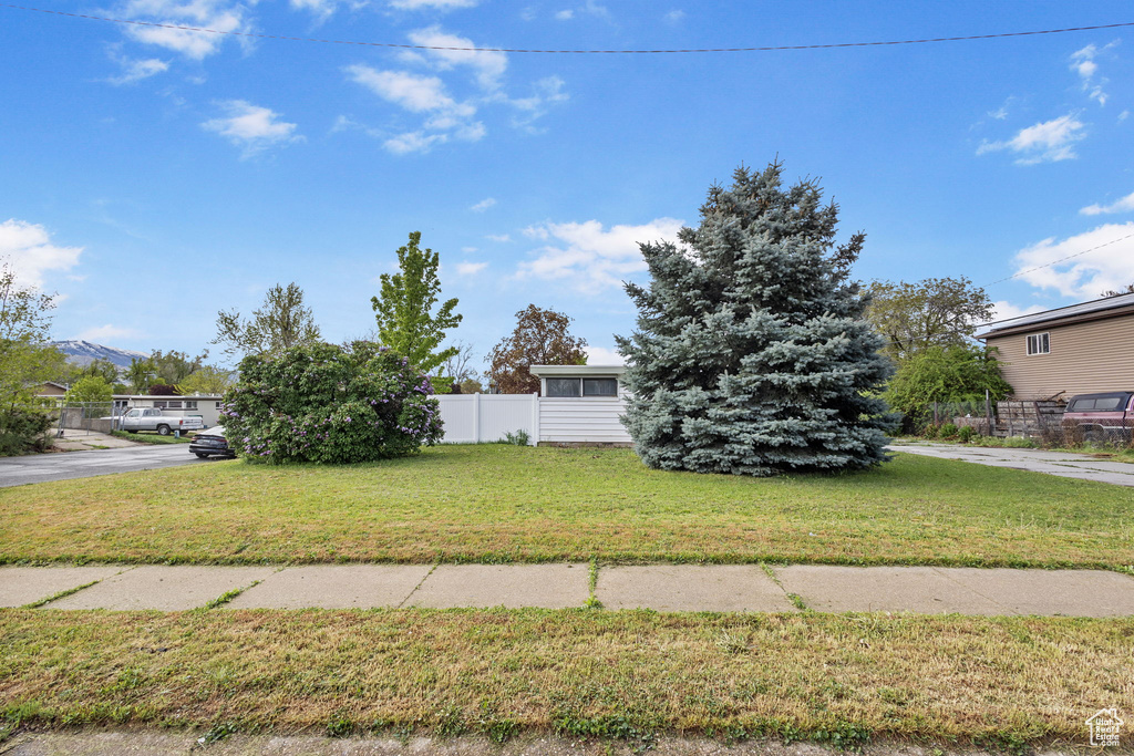 Obstructed view of property featuring fence and a front yard