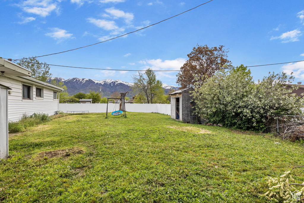 View of yard featuring an outbuilding, a mountain view, a fenced backyard, and a storage unit
