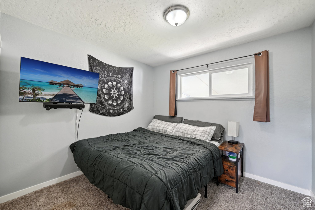 Carpeted bedroom featuring a textured ceiling and baseboards