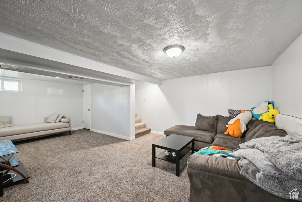 Living room with carpet floors, baseboards, visible vents, and stairway