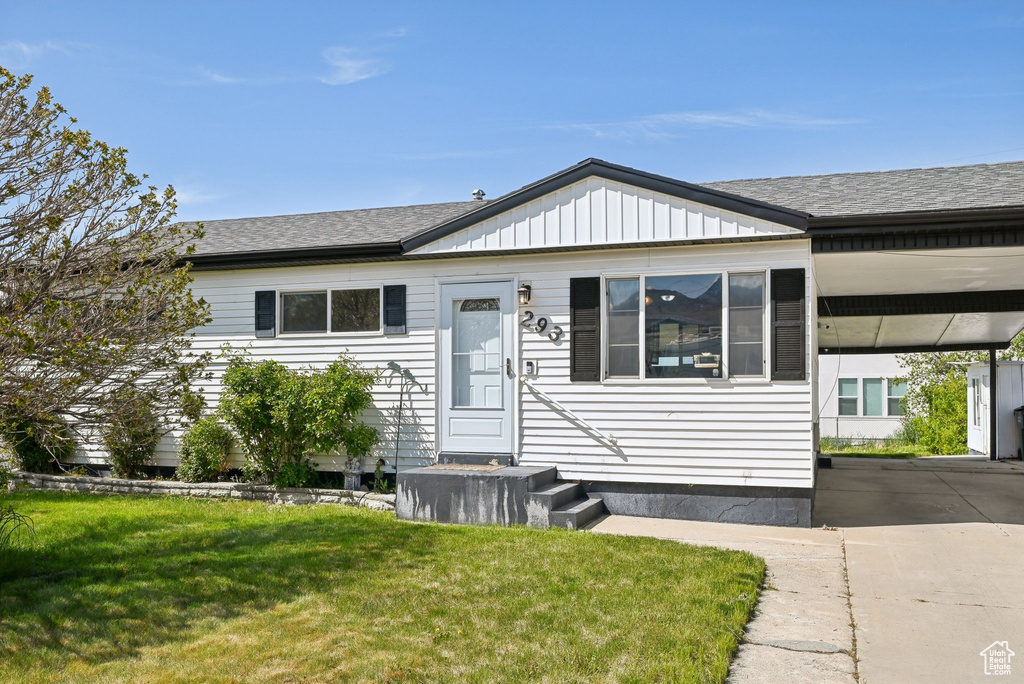 View of front of house with a shingled roof, a front lawn, and a carport