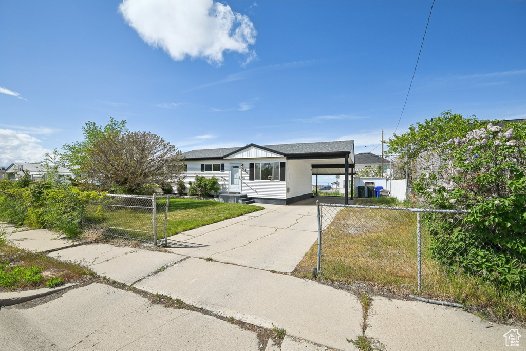 Ranch-style home with fence, a front lawn, an attached carport, a gate, and driveway