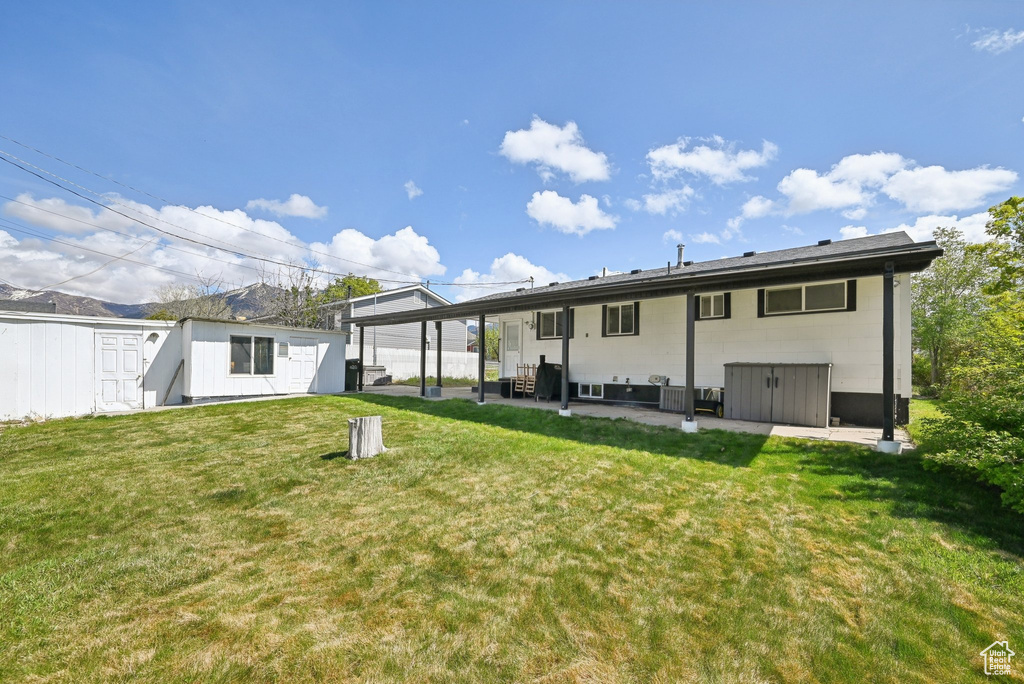 Back of property featuring a yard, a patio, and an outbuilding