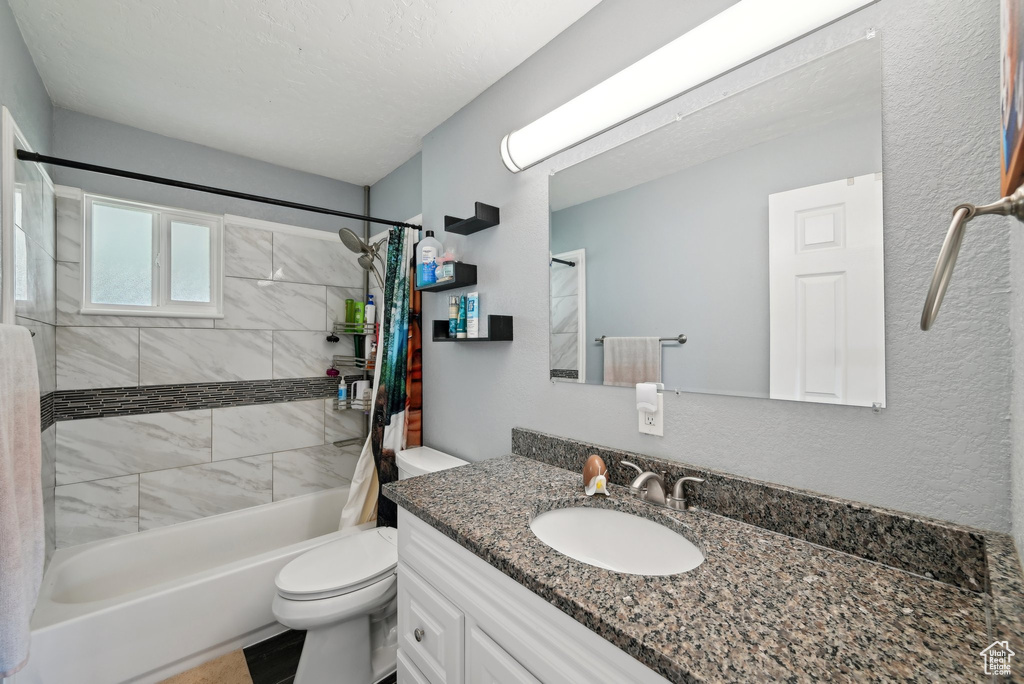 Full bath with vanity, shower / bath combo with shower curtain, and toilet
