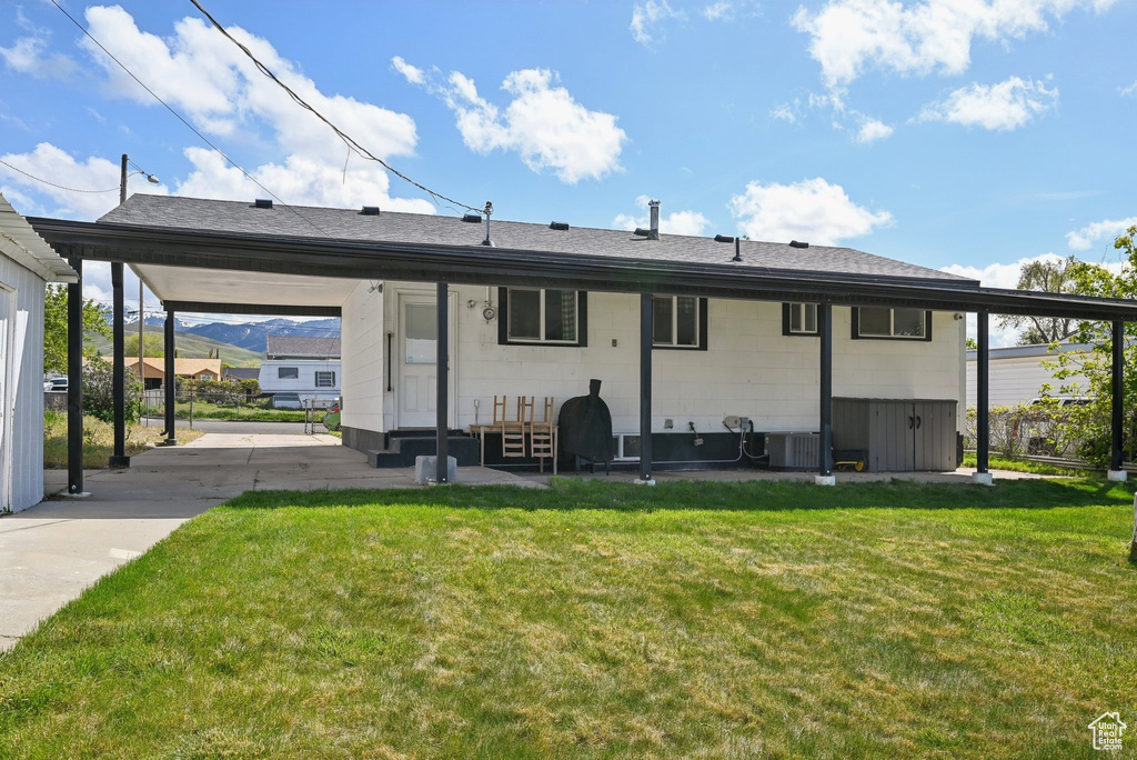 Back of property featuring a lawn, central AC unit, and entry steps