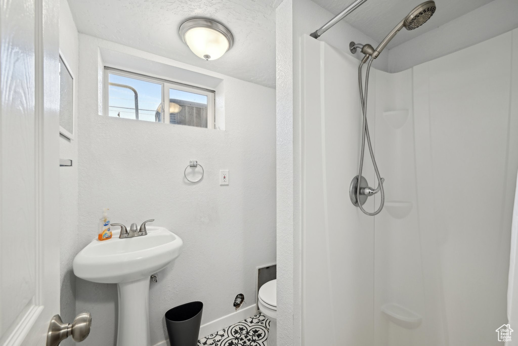 Bathroom with a sink, baseboards, toilet, and a shower