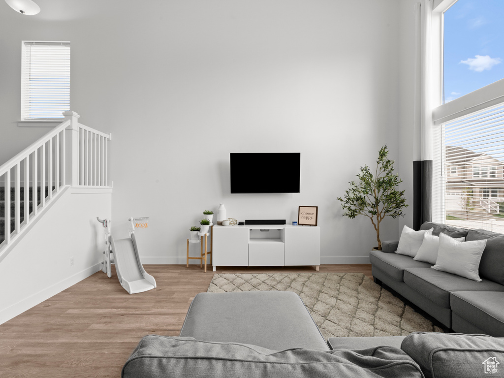 Living area with baseboards, wood finished floors, and a towering ceiling