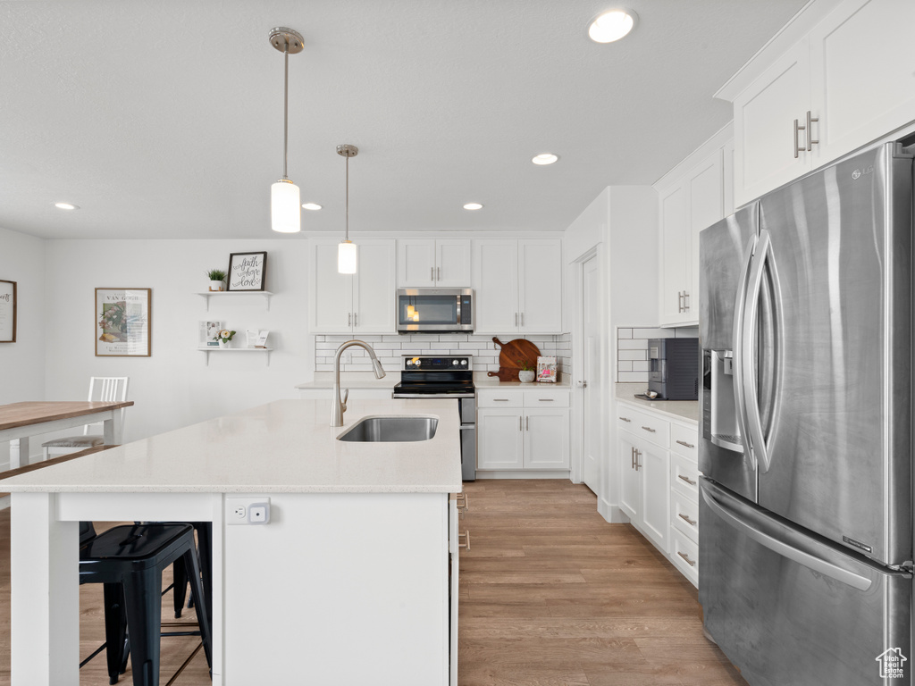 Kitchen featuring light wood-style floors, recessed lighting, white cabinetry, a sink, and stainless steel appliances