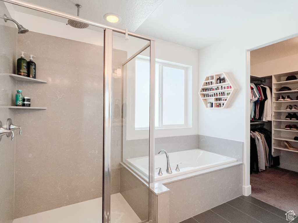 Full bathroom with a bath, a spacious closet, and a shower stall