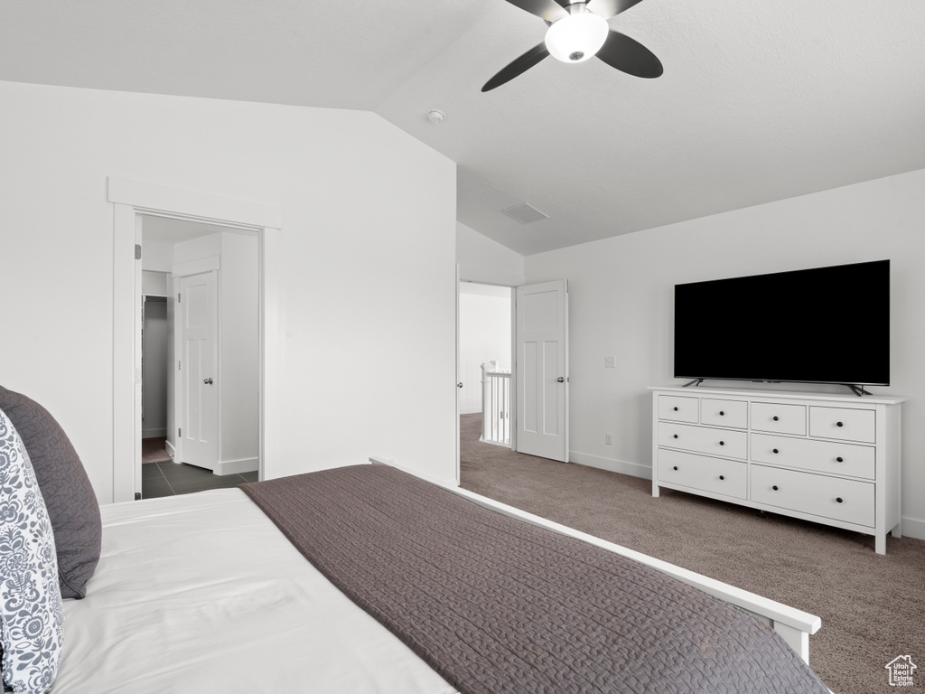Carpeted bedroom with baseboards, visible vents, ceiling fan, and lofted ceiling