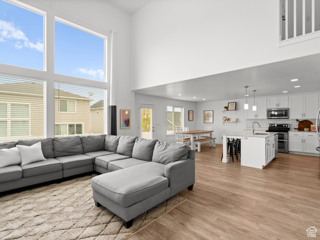 Living room featuring recessed lighting, light wood finished floors, and a high ceiling
