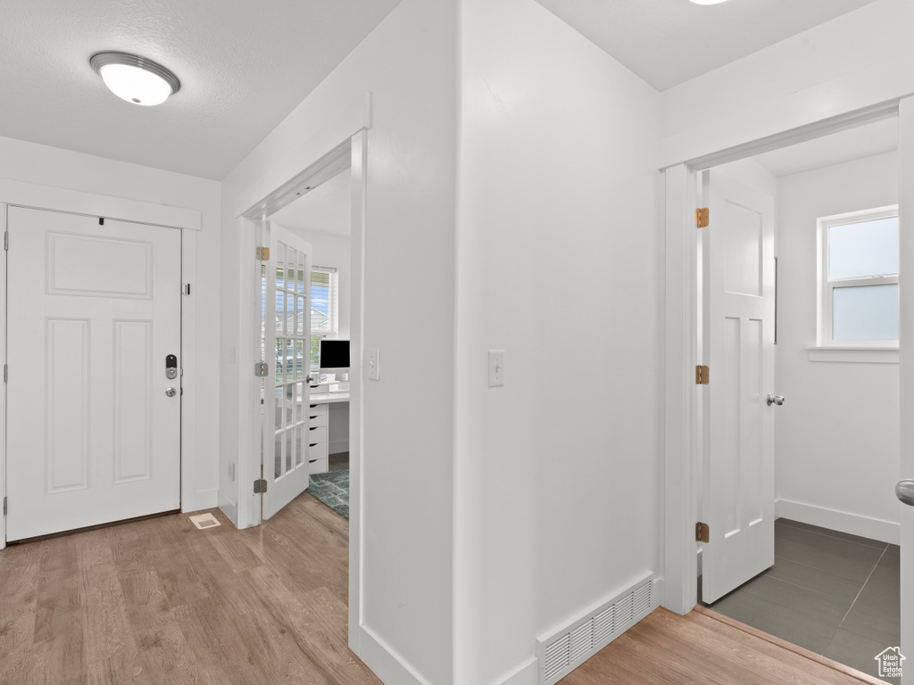 Entryway with baseboards, light wood finished floors, and visible vents