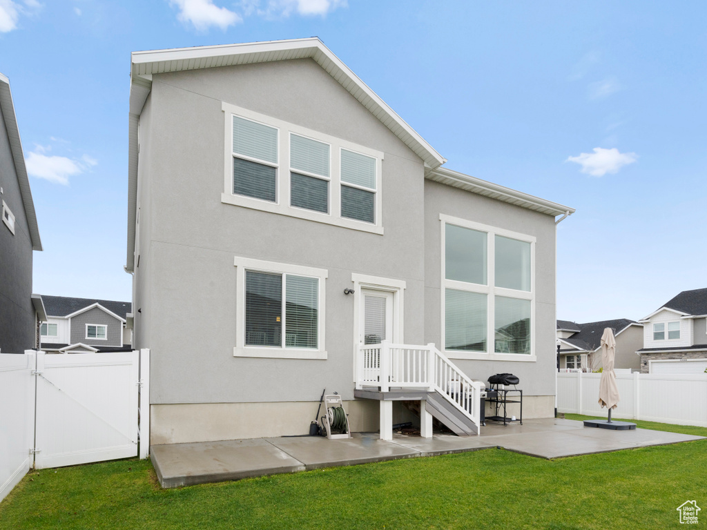 Rear view of house with fence, a gate, stucco siding, and a patio area