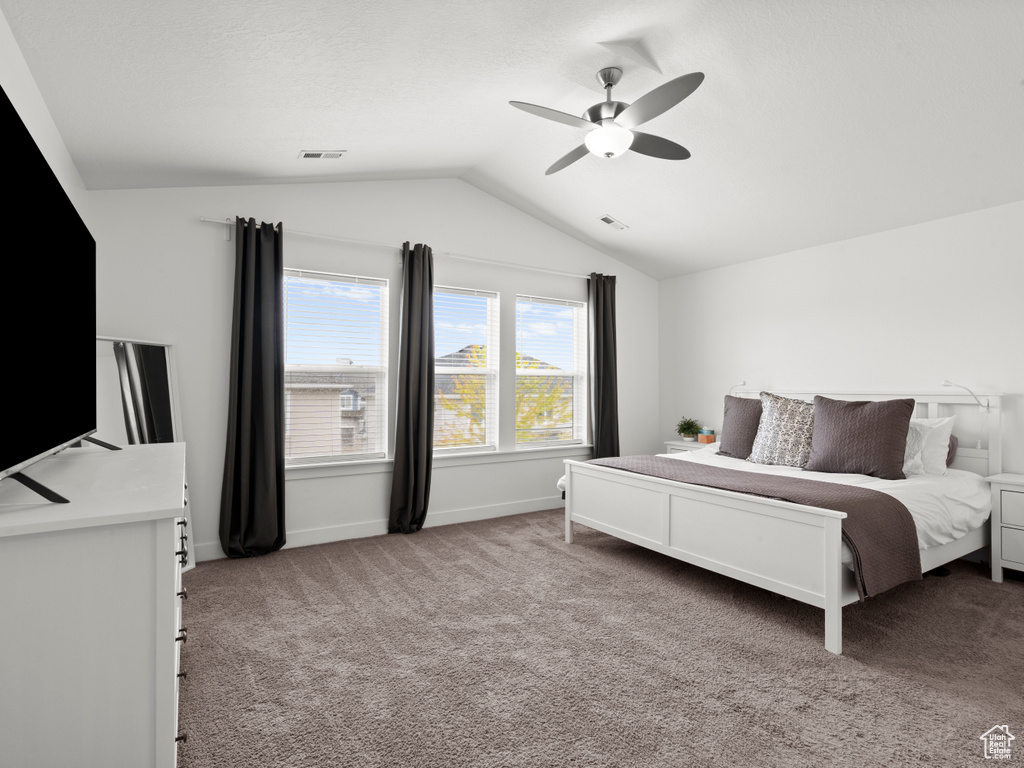 Bedroom featuring visible vents, lofted ceiling, light carpet, baseboards, and a ceiling fan