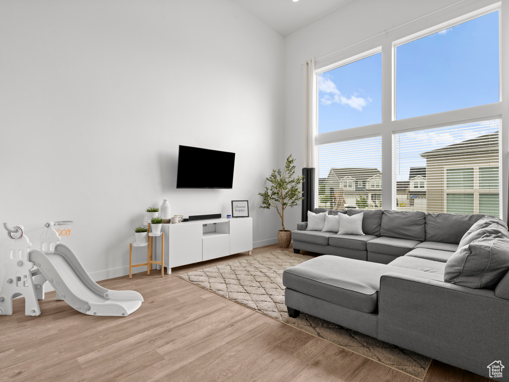 Living area with baseboards, a towering ceiling, and wood finished floors