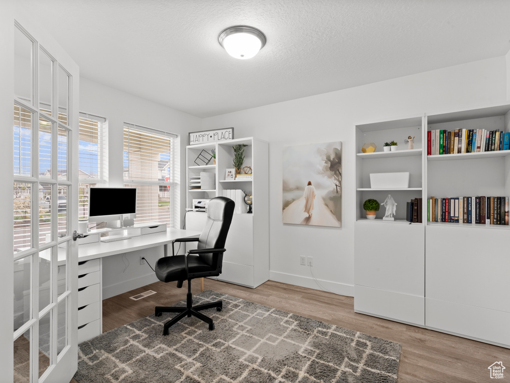Office with baseboards, visible vents, and wood finished floors