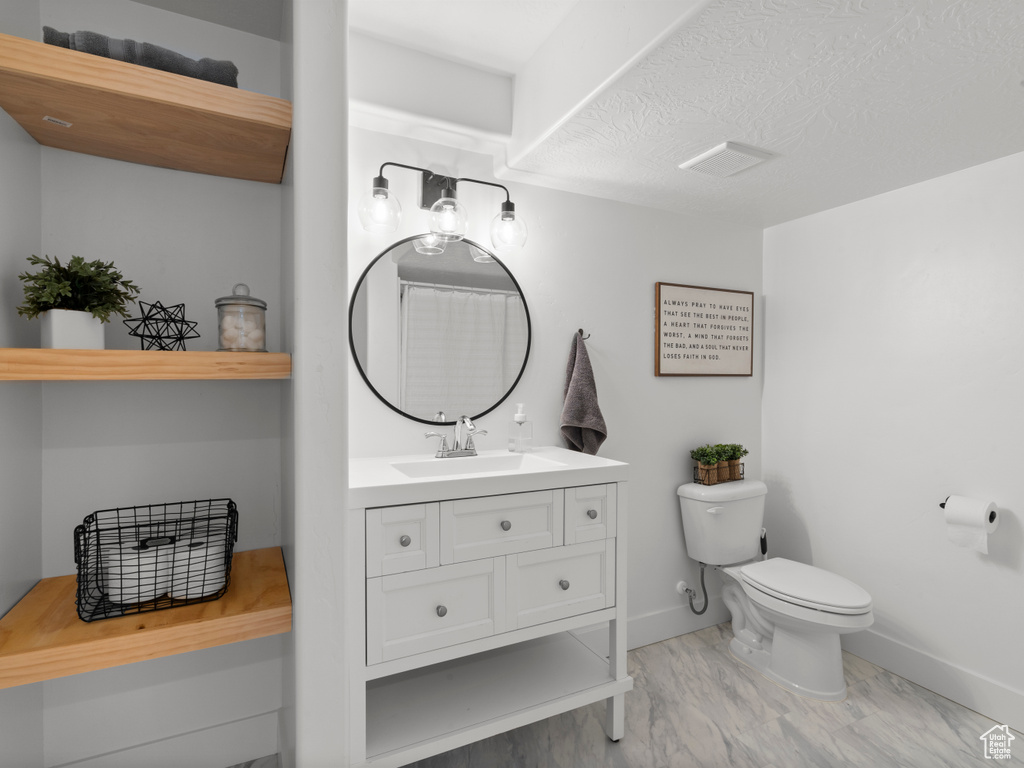 Bathroom featuring toilet, baseboards, and vanity