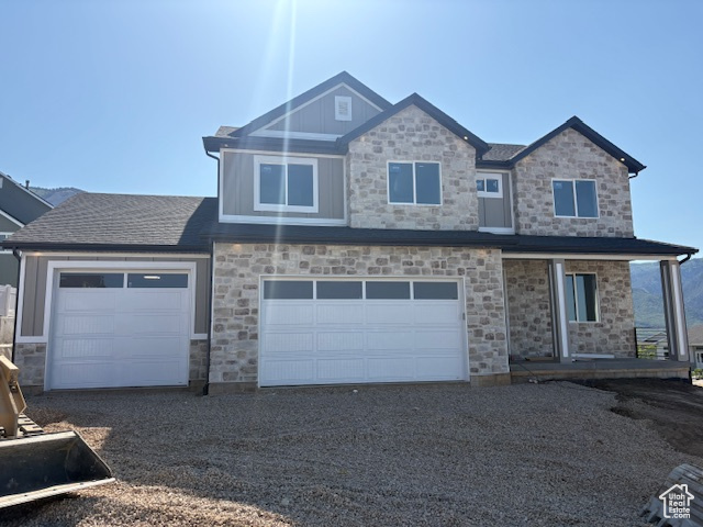 View of front of home featuring stone siding, gravel driveway, and covered porch