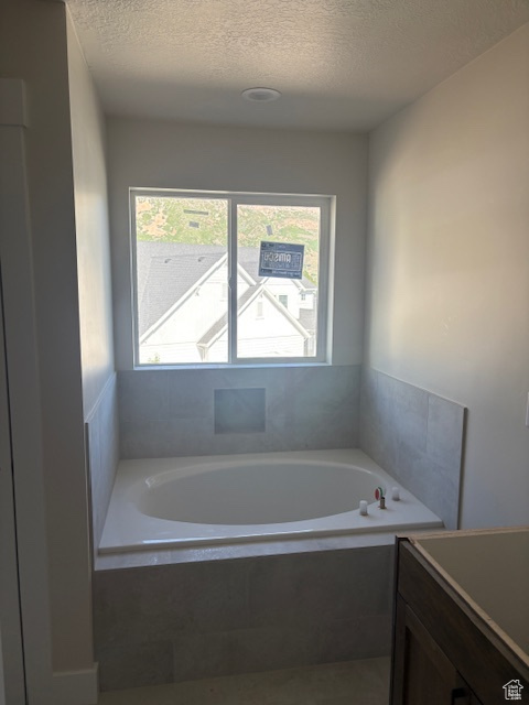 Full bath with a bath, a textured ceiling, and vanity