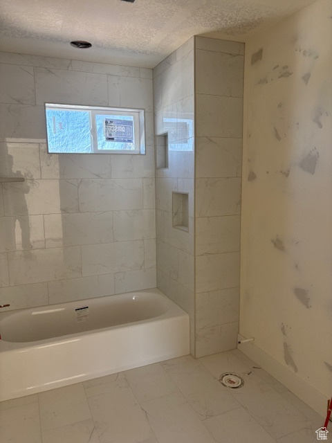 Full bath with a textured ceiling and shower / washtub combination