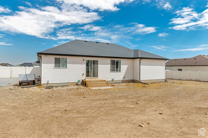 Back of property with roof with shingles and fence