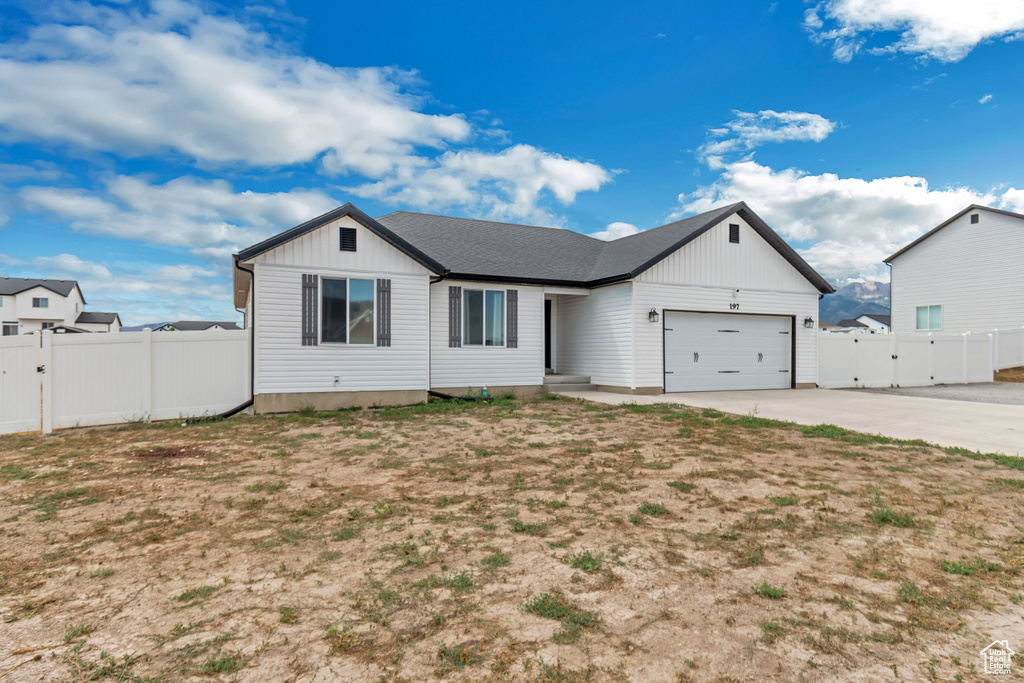 Single story home featuring an attached garage, board and batten siding, fence, a gate, and driveway