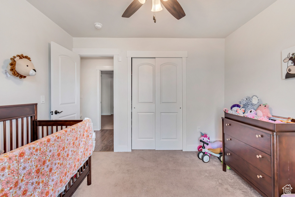 Bedroom featuring a closet, light colored carpet, and a ceiling fan