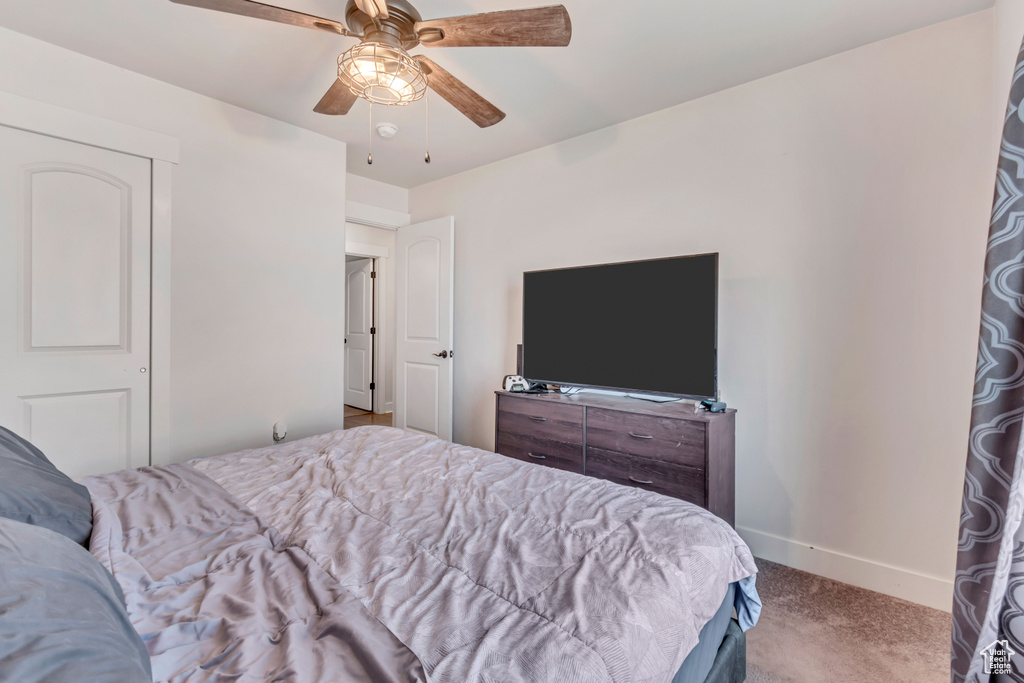 Carpeted bedroom featuring ceiling fan and baseboards