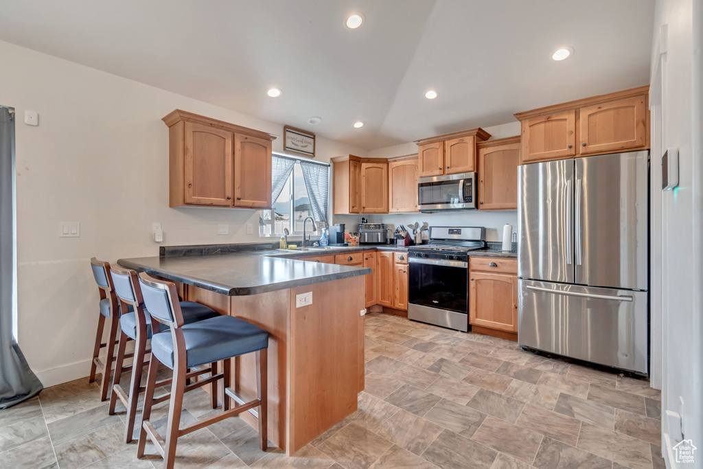 Kitchen with a kitchen breakfast bar, recessed lighting, a peninsula, dark countertops, and stainless steel appliances