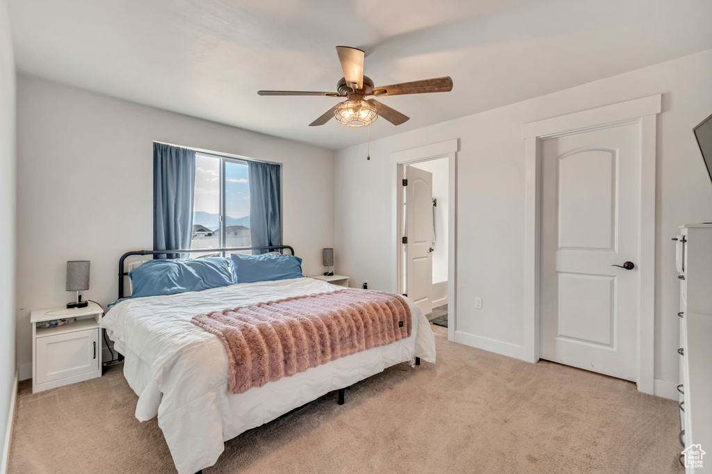 Bedroom featuring ceiling fan, connected bathroom, and light colored carpet