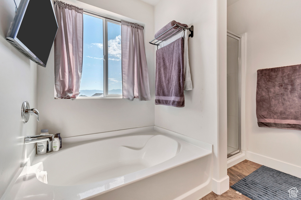 Full bathroom featuring a bath, a stall shower, and baseboards