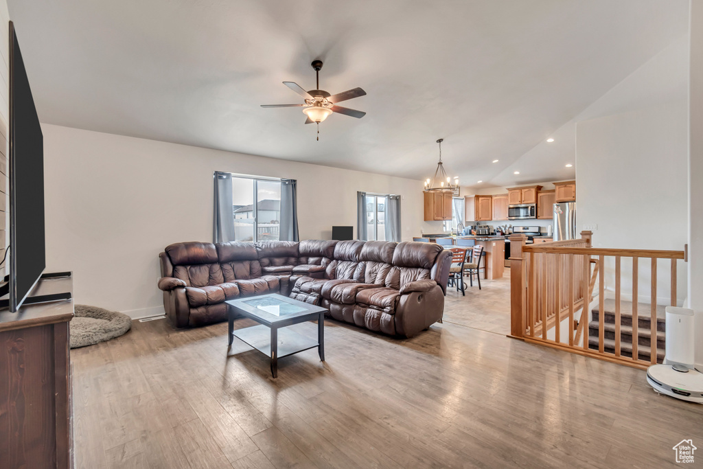 Living area with recessed lighting, light wood-style floors, and ceiling fan with notable chandelier