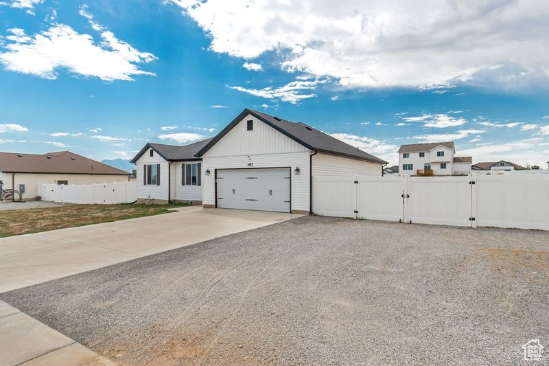 Modern inspired farmhouse with concrete driveway, a gate, board and batten siding, a garage, and fence