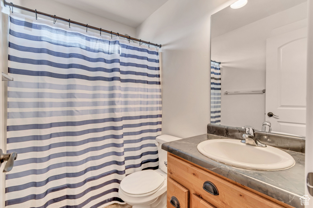 Bathroom with vanity, a shower with curtain, and toilet