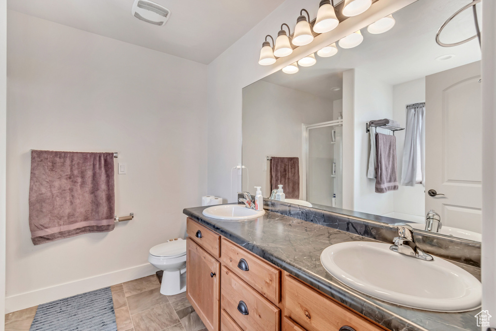 Bathroom with a stall shower, double vanity, a sink, and baseboards