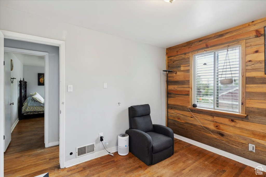 Sitting room with visible vents, wood walls, and wood finished floors